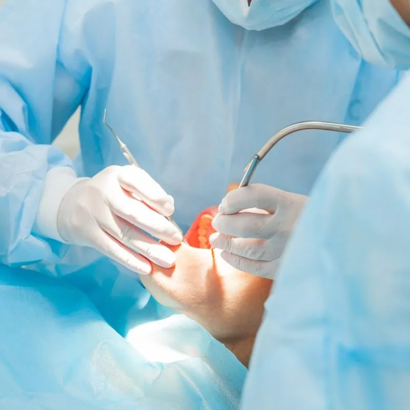 Someone under anesthesia while a dentist performs oral surgery